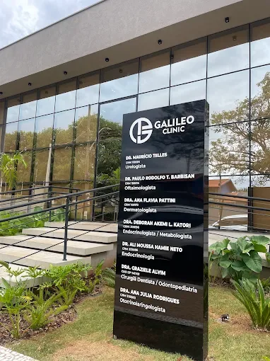 Placa externa da Galileo Clinic com a relação de profissionais e especialidades.